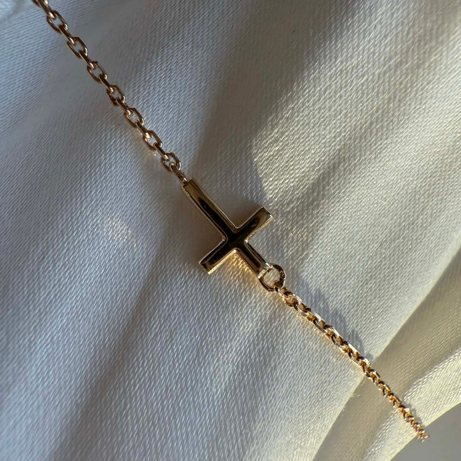 Kors armbånd i 18 kt guld - vist på klæde