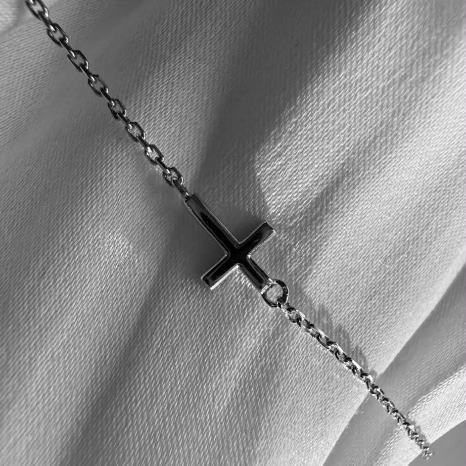 Kors armbånd i 18 kt hvidguld - vist på klæde close up