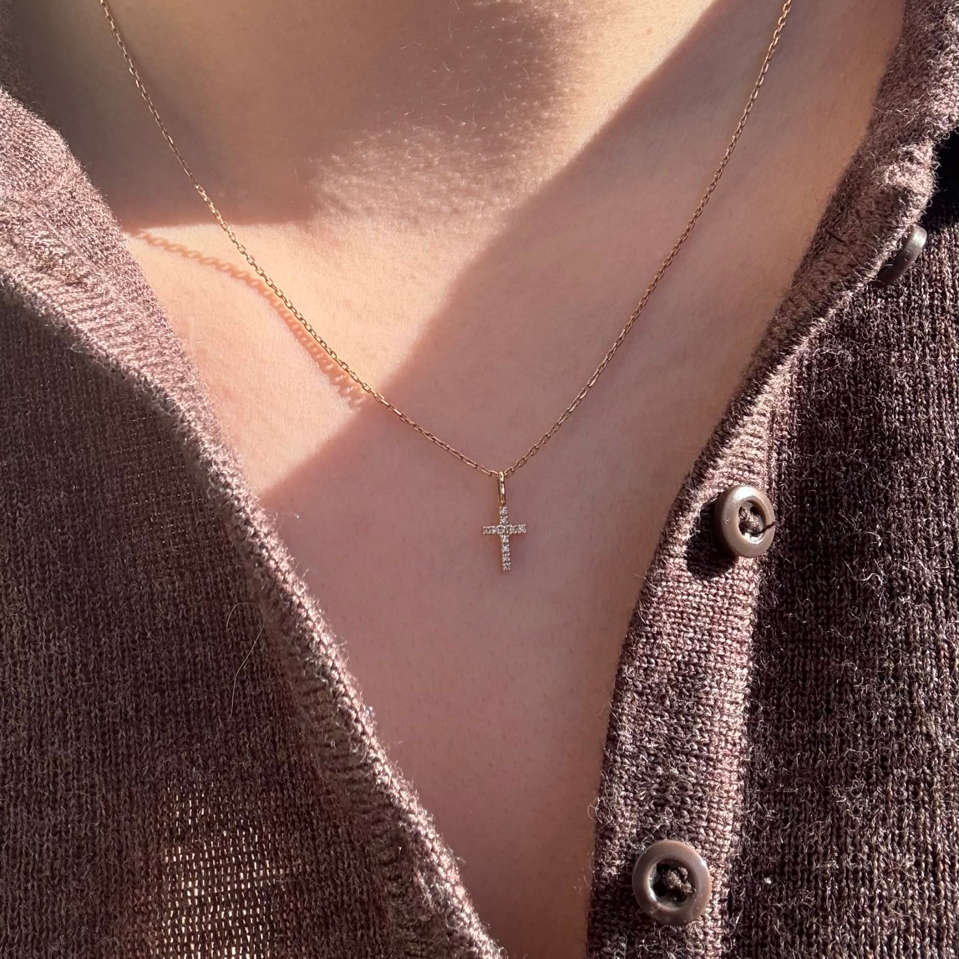 Kors vedhæng i 18 kt guld med brillantslebne diamanter på 0,05 ct – vist på model