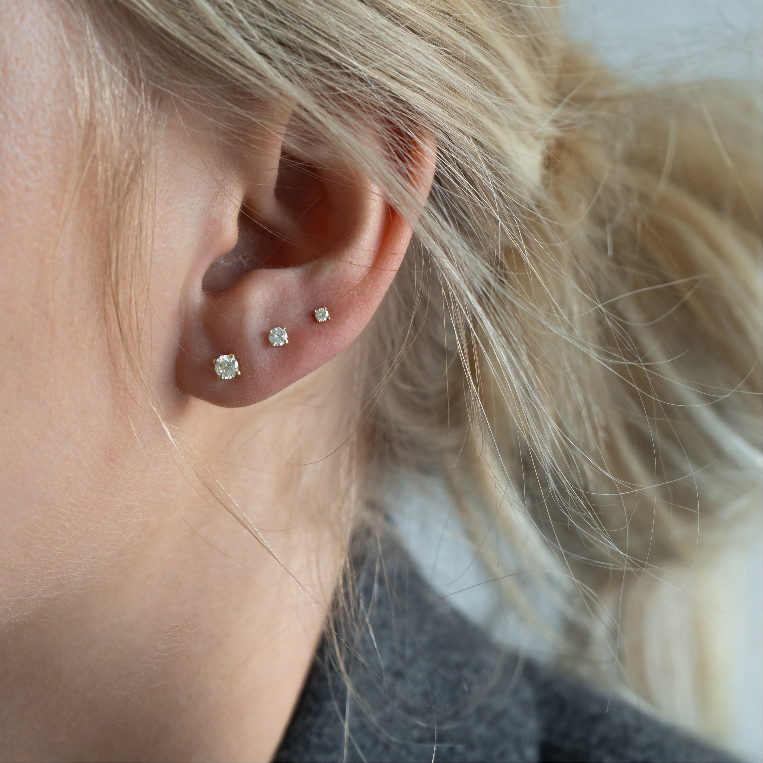 Solitaire ørestikker i 18 kt guld med diamanter – båret på model